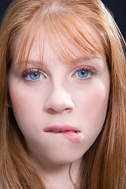 young woman with red hair biting lip - biting lip imagens e fotografias de stock