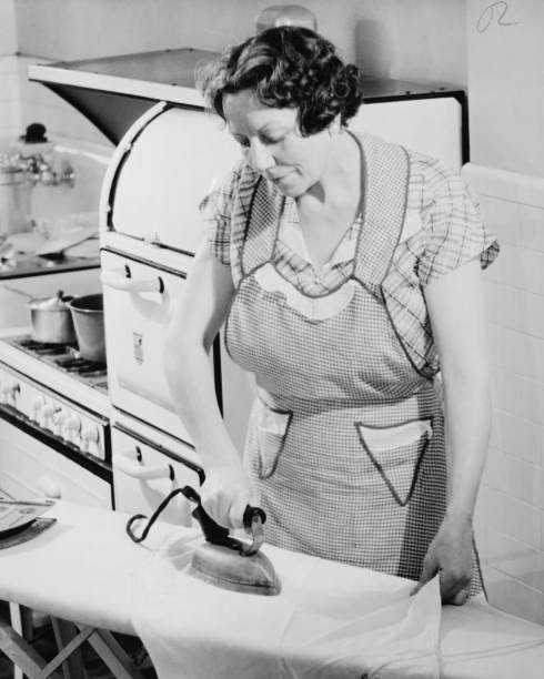 donna stiratura in cucina, (b & w - stereotypical homemaker foto e immagini stock