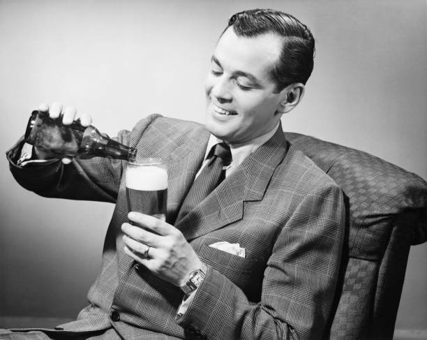 elegante homem servindo cerveja de garrafa em vidro, & (b w - cabelo com gel para trás - fotografias e filmes do acervo
