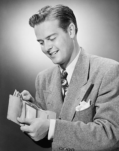 Elegant man putting US dollar's bills into wallet, (B&W)  slicked back hair stock pictures, royalty-free photos & images