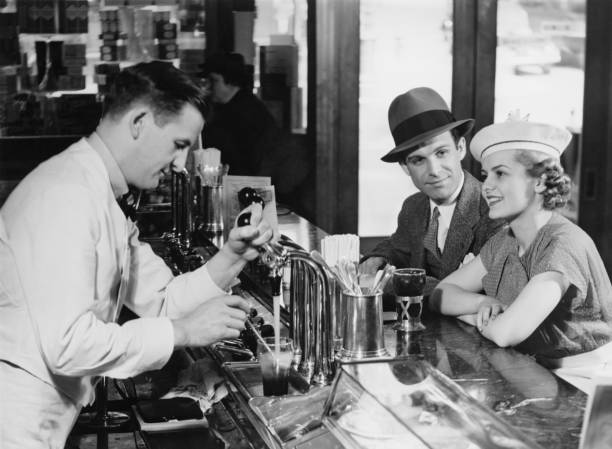 バーテンダーのビールを注ぐ若いカップルのバー（b &w - men fedora hat 1940s style ストックフォトと画像
