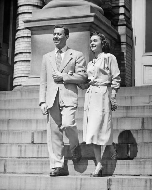 elegante coppia discendente di passi, (b & w - 1950s style couple old fashioned heterosexual couple foto e immagini stock