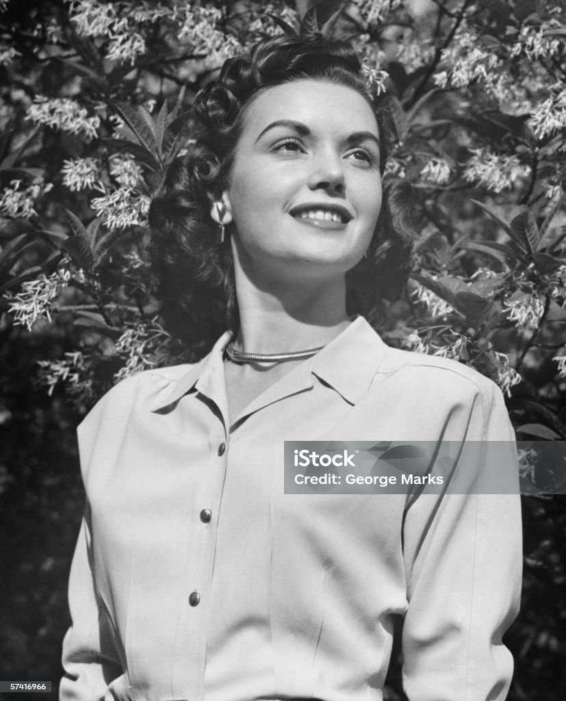 Joven mujer posando por árbol de flor abriéndose - Foto de stock de Mujeres libre de derechos