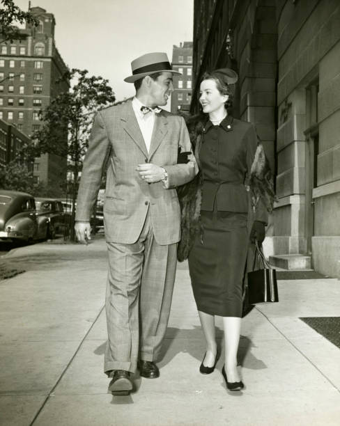 elegante par caminar sobre la acera, (b & p - men fedora hat 1940s style fotografías e imágenes de stock