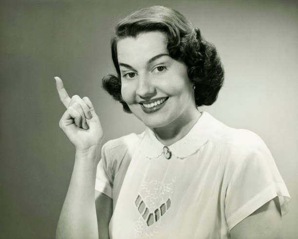 Smiling woman pointing finger in studio, (B&W), (Close-up), (Portrait)  vintage women stock pictures, royalty-free photos & images