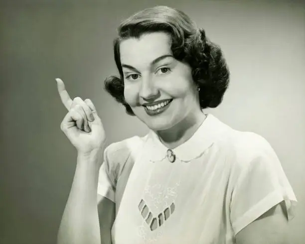 Photo of Smiling woman pointing finger in studio, (B&W), (Close-up), (Portrait)