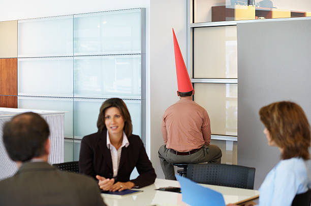 Businessman sat in corner with dunce cap  exclusion group of people separation fish out of water stock pictures, royalty-free photos & images