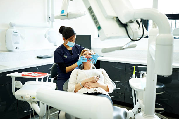 dentista que examina los dientes de la mujer madura - medical exam dentist dentists chair dental assistant fotografías e imágenes de stock