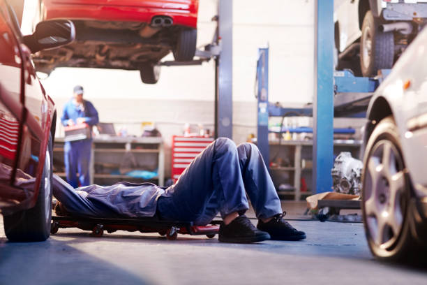 mecánico debajo del automóvil en el taller de reparación de automóviles - mechanic fotografías e imágenes de stock