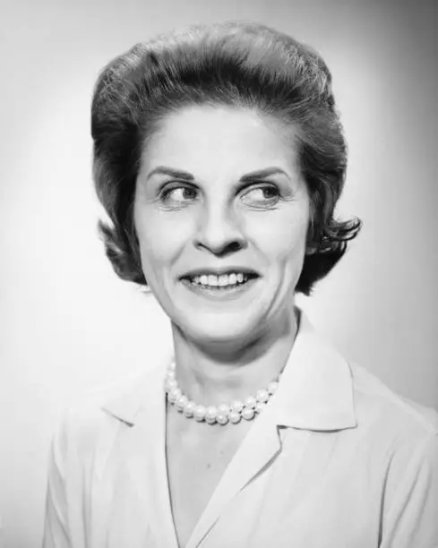 Photo of Woman wearing pearls  smiling, looking away, posing in studio, (B&W), portrait