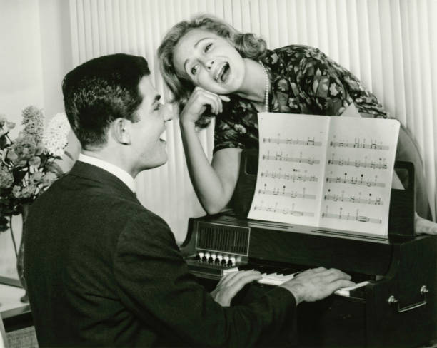 Young couple singing, man playing piano, (B&W)  sheet music photos stock pictures, royalty-free photos & images