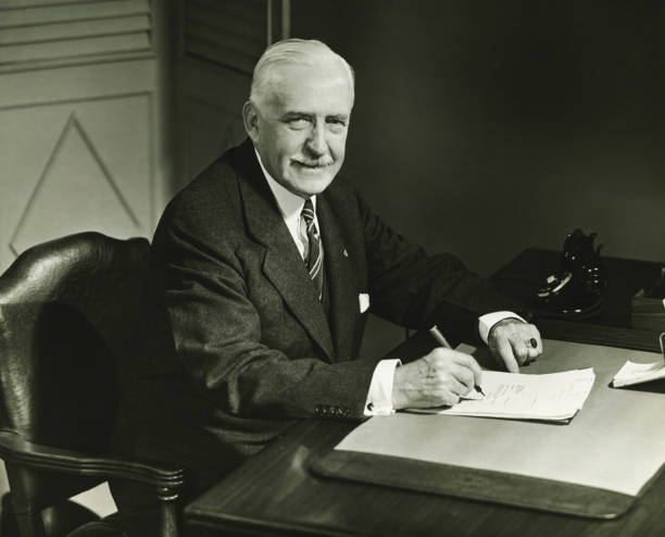 Senior businessman signing documents at desk, (B&W), portrait  signing photos stock pictures, royalty-free photos & images