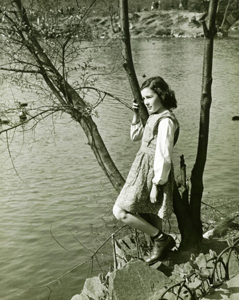 menina (8-9) inclinar-se em tronco de árvore com água (b & m), - lonely tree fotos imagens e fotografias de stock