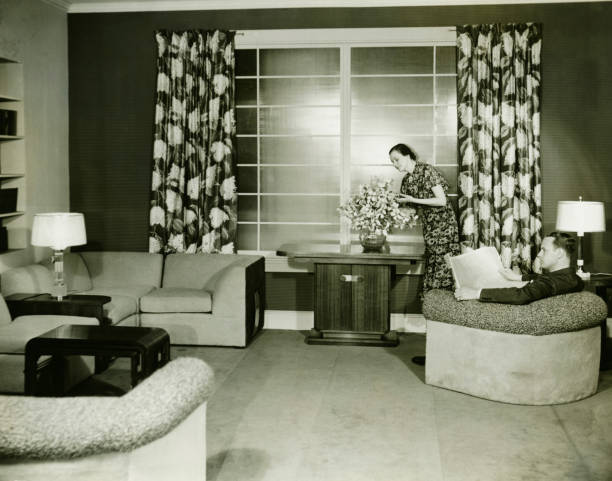 femme faisant composition florale, homme assis dans la salle de séjour - 40s couple women house photos et images de collection