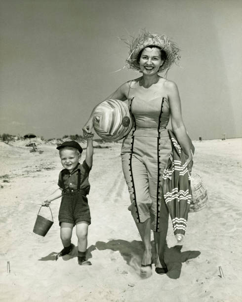 Mother with son (2-3) walking on beach, (B&W), portrait  black and white beach stock pictures, royalty-free photos & images