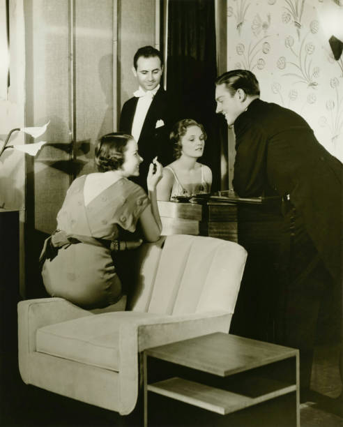 deux jeunes couples sont réunis autour du piano dans la salle de séjour (b & w - 40s couple women house photos et images de collection