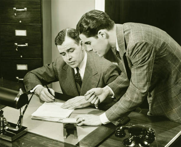Two young businessmen talking at small desk, (B&W)  fountain pen photos stock pictures, royalty-free photos & images