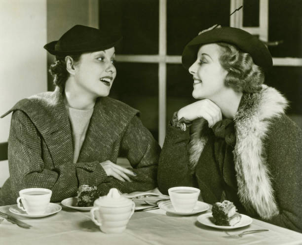dos mujeres jóvenes conversar, disfruta de un café y una porción de torta (b & p - coffee buzz fotografías e imágenes de stock
