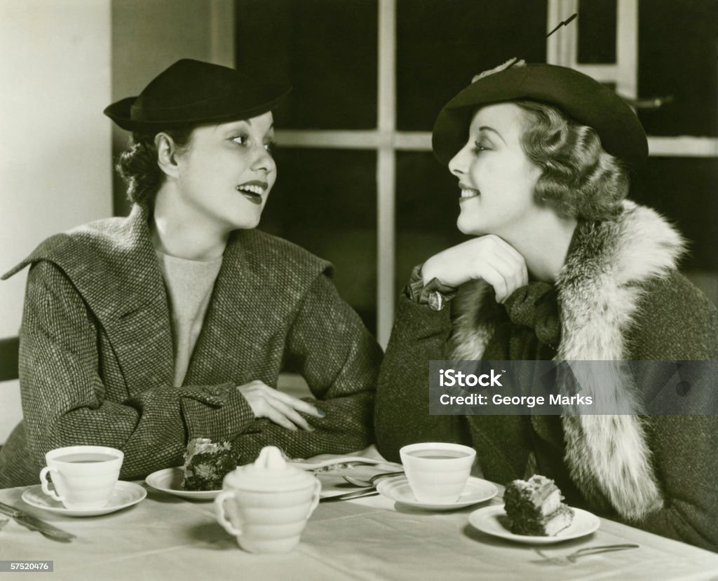 Duas jovens mulheres conversando, tendo o café e bolo, & (B W - Foto de stock de Mulheres royalty-free