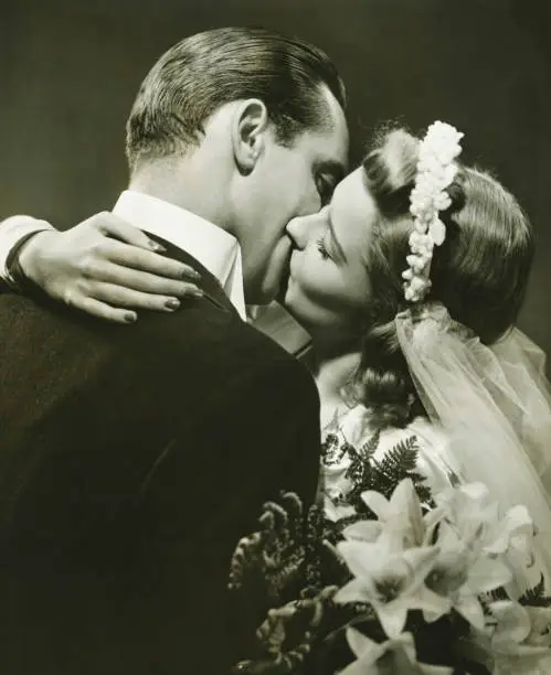 Photo of Bride and Groom kissing in studio, (B&W)