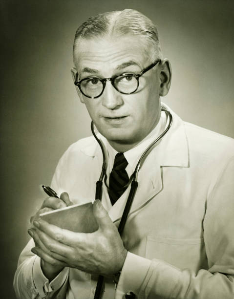 Doctor holding note pad posing in studio, (B&W), portrait  drug photos stock pictures, royalty-free photos & images