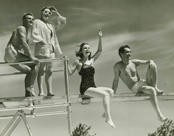 Photo of Two couples on springboard, (B&W), low angle view