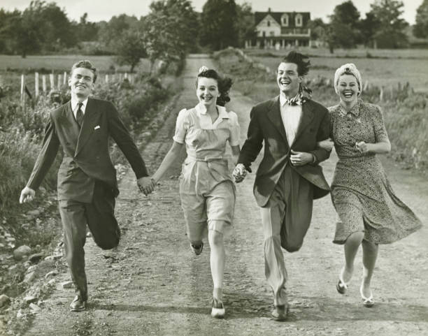 Two couples holding hands, running on footpath, (B&W)  vintage people stock pictures, royalty-free photos & images