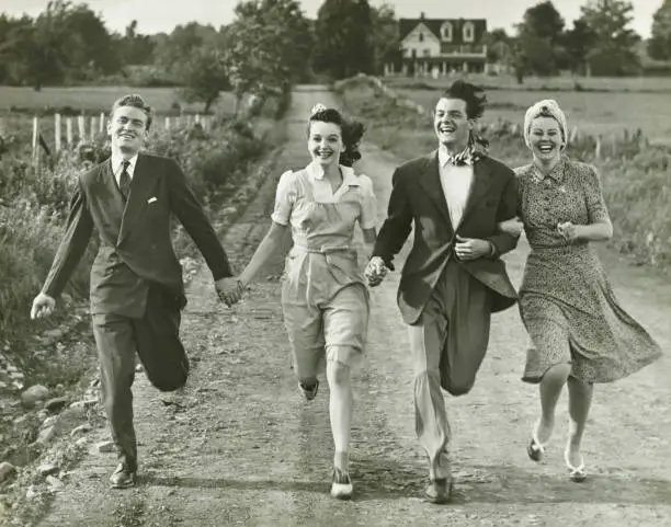Photo of Two couples holding hands, running on footpath, (B&W)