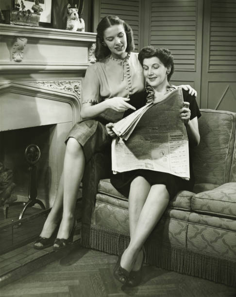duas mulheres sentado pela lareira leitura de jornais (b & m - reading newspaper 30s adult imagens e fotografias de stock