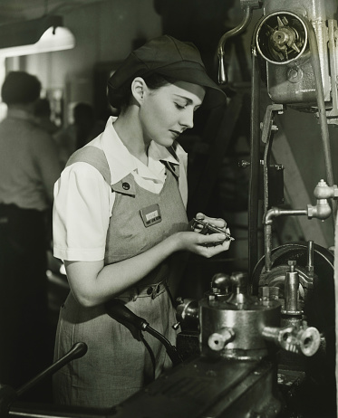 A young woman works as an industrial\ncomputer controller. She is seen at\nher workplace wearing a blue overall.
