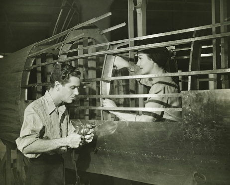 Joven y mujer trabajando en avión cuerpo en fábrica, (B & P photo