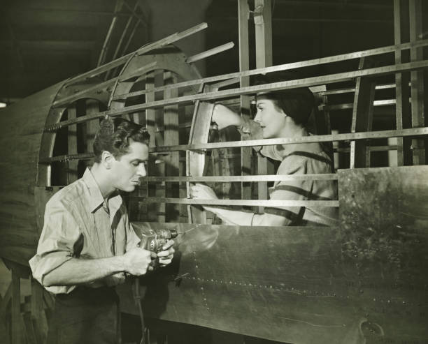 joven y mujer trabajando en avión cuerpo en fábrica, (b & p - 1930 fotografías e imágenes de stock