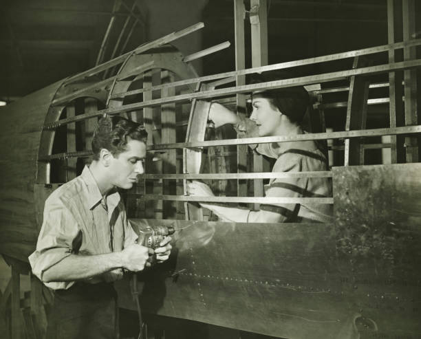 Young man and woman working in plane body in factory, (B&W)  world war ii photos stock pictures, royalty-free photos & images