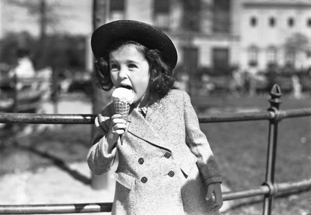 Elegant girl (4-5) eating ice crem outdoors, (B&W)  frozen sweet food photos stock pictures, royalty-free photos & images