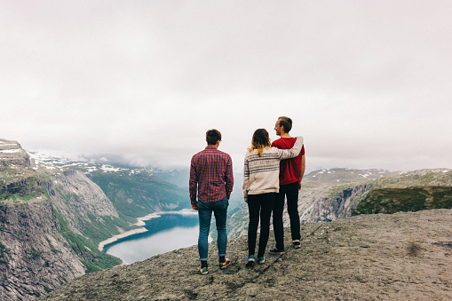 Three young adults standing on the edge of the Trolltunga rock 