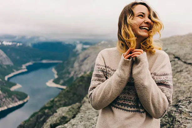 Girl standing on the Trolltunga and laughing 