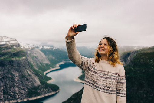 Woman take selfie on Trolltunga rock in Norway 