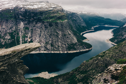 Young caucasian woman standing on Trolltunga in Norway 
