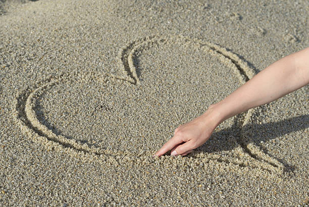 istock Drawing hearts in the sand 576547356