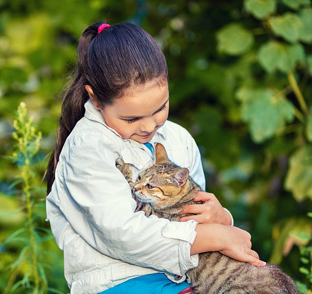 istock Little girl hugging a stray cat in the park 576554752