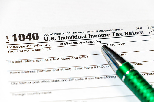 1040 Individual Income Tax Return Form with a pen to fill on the white desk, close up