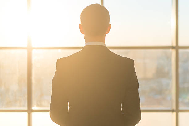 istock Rear view of a male office worker looking at window 576557392