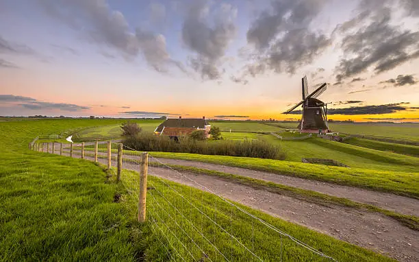 Photo of Dutch Wooden windmill in flat grassy landscape