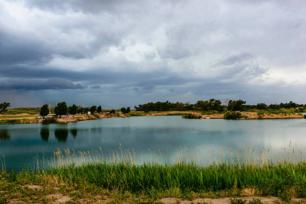 A gathering rain storm builds over a rural fishing pond and camp ground in western Kansas.