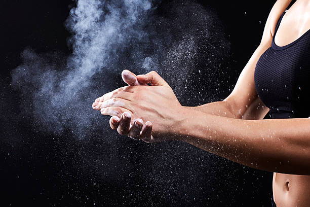 istock Muscular woman coating her hands in powder chalk 576573404