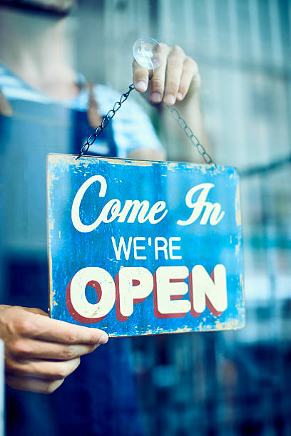 istock Barista hanging an open sign in coffee shop 576574568