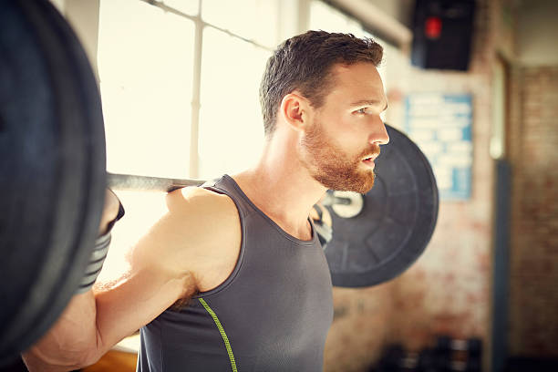 istock Side view of confident man picking up barbell in gym 576575520