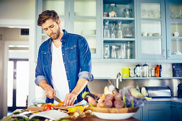 istock Young man cutting vegetables at kitchen island 576575726