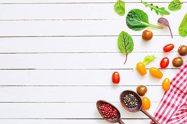 Food ingredients for healthy cooking Fresh cherry tomatoes, salad leaves and spices on white wooden background with copy space. Healthy cooking background, good for menu, recipe or web sites banner. salad fruit lettuce spring stock pictures, royalty-free photos & images