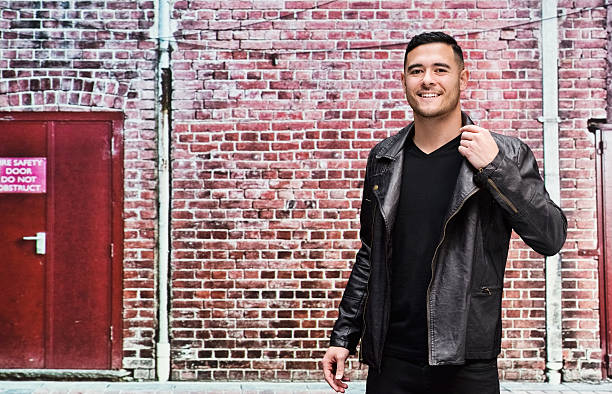 istock Smiling man standing in front of brick wall 576577274